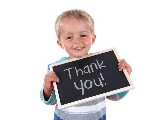 Child holding thank you on a chalk board