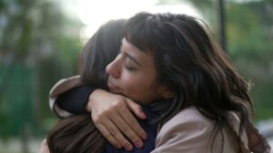 close up of woman giving another female a comforting hug