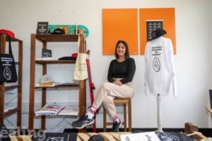 Asian woman sitting on a stool net to mannequin in a shop of  Southall souvenirs next