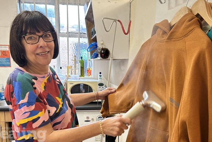 Woman with steam cleaner cleaning a brown jacket