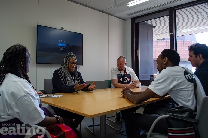 Office with table and 5 adults sitting around speaking