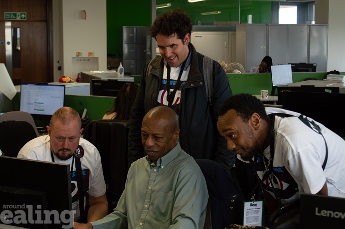 4 male adults, 3 sitting, 1 standing, looking at a computer screen