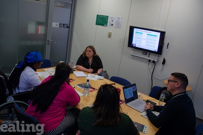 5 adults in an office sitting around a meeting table