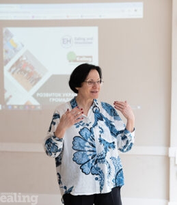 woman having a talk in a room with screen behind her