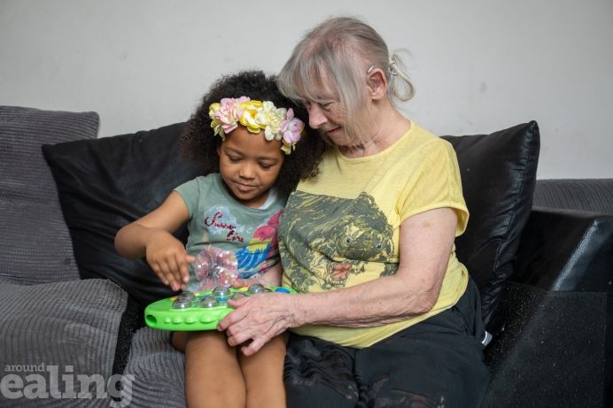 Little girl and older woman sitting together on a sofa playing a board game.