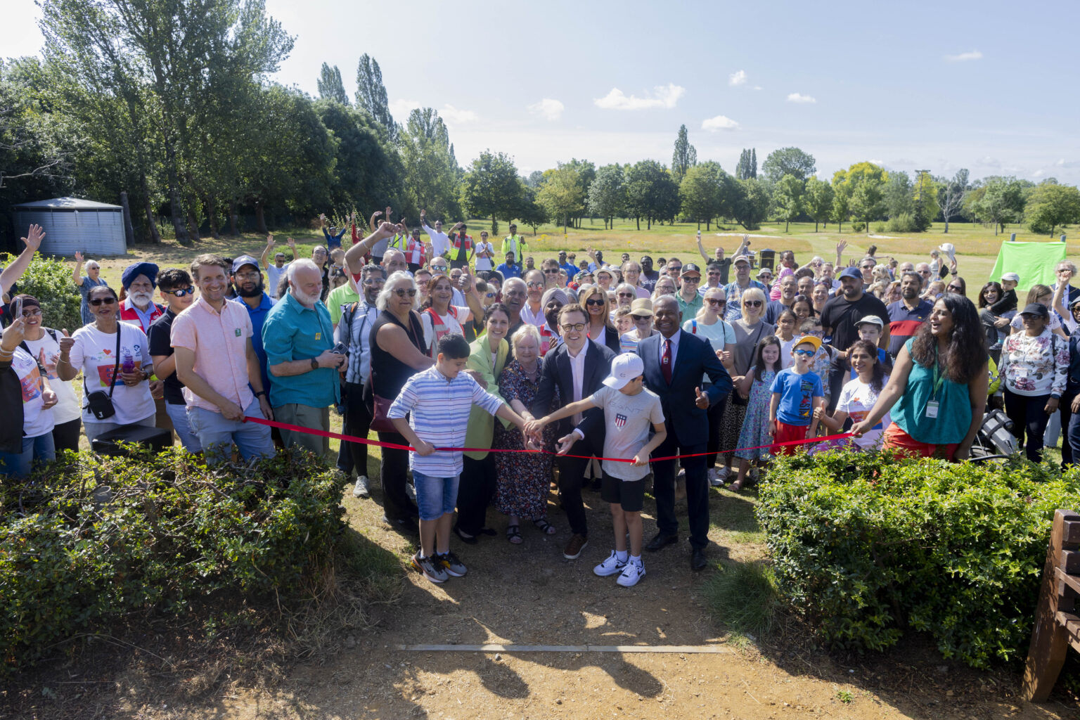 A large group of people at a ribbon cutting ceremony at Pear Tree Park