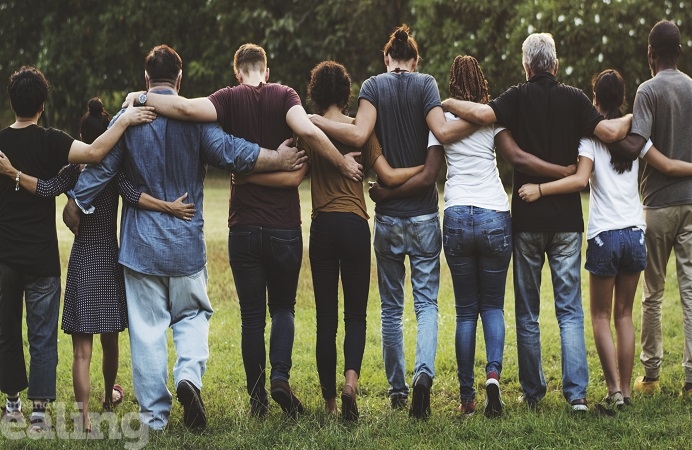 Group of friends huddle together with linked arms in rear view together