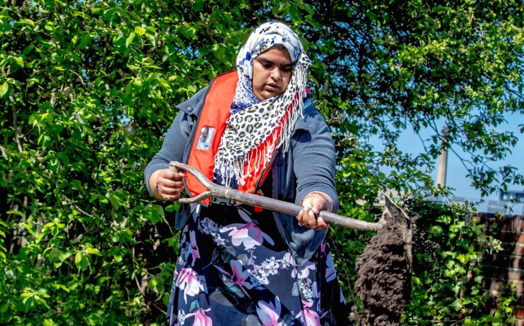 Woman using a shovel to pour earth into a box.