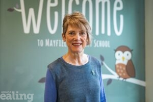 smiling woman in front of school welcome sign