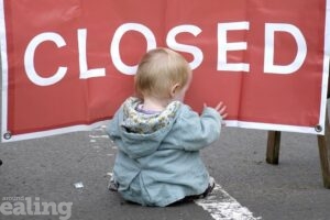 baby sitting in road in front of closed sign