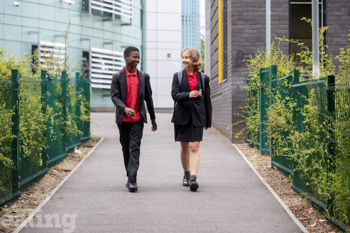 boy and girl in school uniform walking away from school smiling