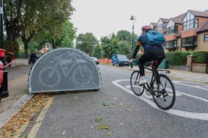 man cycling on road past a bike hanger