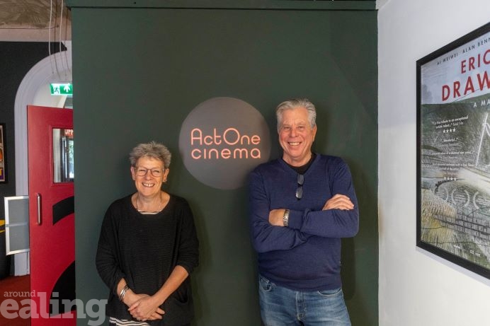 Man and woman standing either side of neon cinema sign