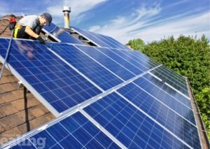 An engineer fixing solar panels to a roof.