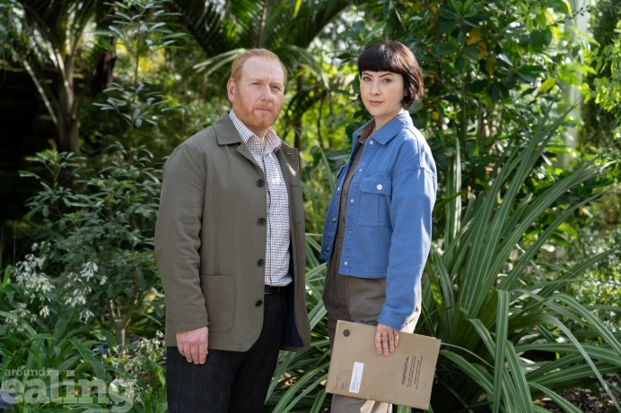 Man and woman standing facing the camera - both are characters from a TV show The Chelsea Detective