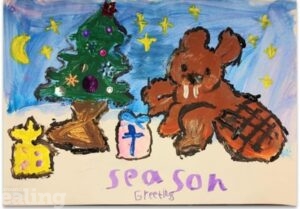 A printed child's hand drawn Christmas card with a brown rabbit next to a Christmas tree, with pink and yellow presents. With the words season greetings.