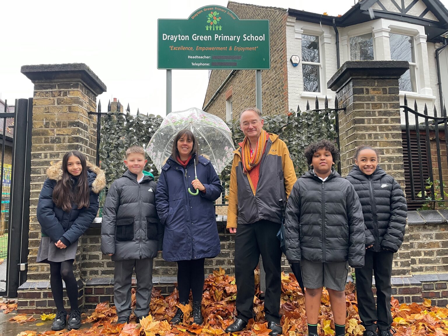 Councillor Paul Driscoll, Deputy Head Laura Richter and four pupils stand outside Drayton Green Primary School.