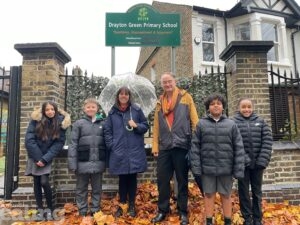 Councillor Paul Driscoll, Deputy Head Laura Richter and four pupils stand outside Drayton Green Primary School.