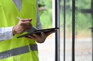 Close up of man in high vis jacket holding clipboard and pen. The council is stepping up HMO inspections.