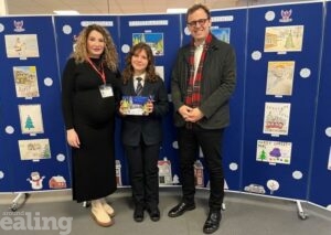 2024 Christmas card winner, Bianca Mocanescu, holding her winning design, standing in between her mother and Councillor Peter Mason.