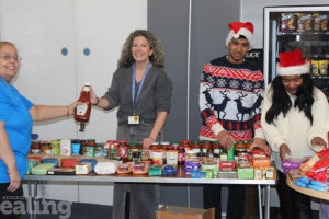 2 women handing out food from a trestle table with the help of a teenage boy