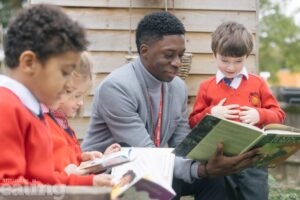 Mr Ross with 3 pupils in the school garden reading books