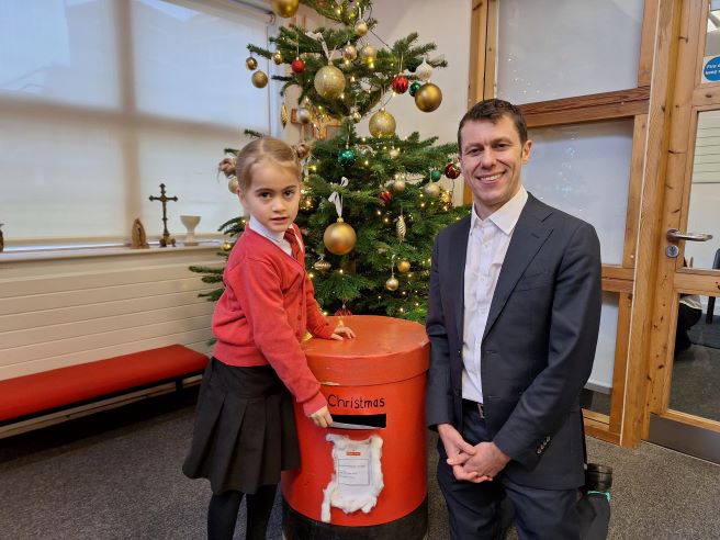 Ealing Council Chief Executive Tony Clements with Christmas card 6 years and under winner Imogen posting her card in a school handmade post box.