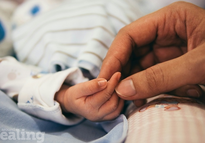 A parent or carer holding a baby's hand