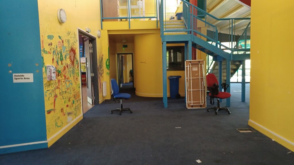 A picture of the former YAC interior. It's yellow and blue, with equipment scattered everywhere and dirt on the floor.