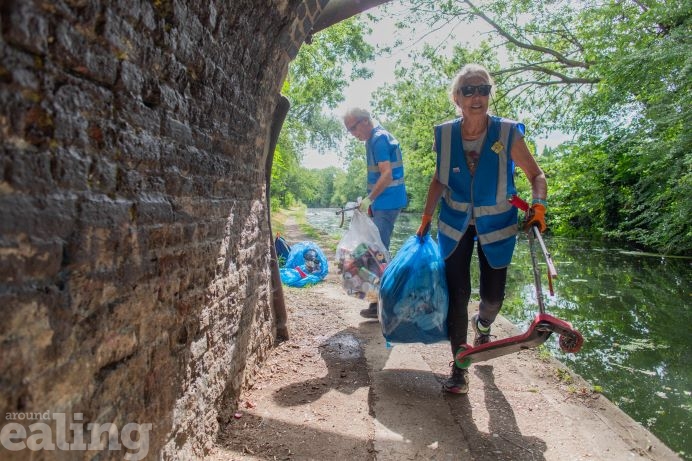 2 volunteers litter picking under a bridge by the Grand Union canal