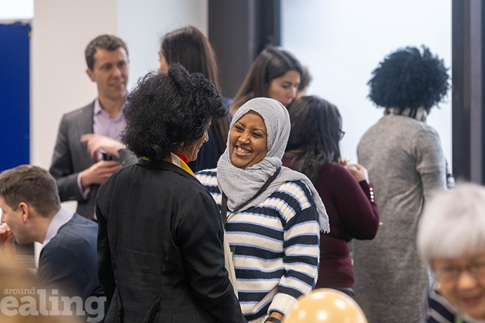 Group of people chatting in a room, with two women sharing a laugh