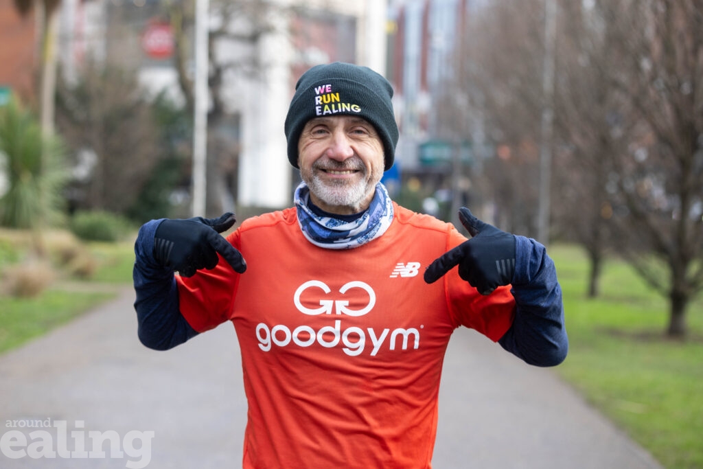 smiling man in running gear pointing to the Good Gym logo on his top