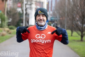 smiling man in running gear pointing to the Good Gym logo on his top