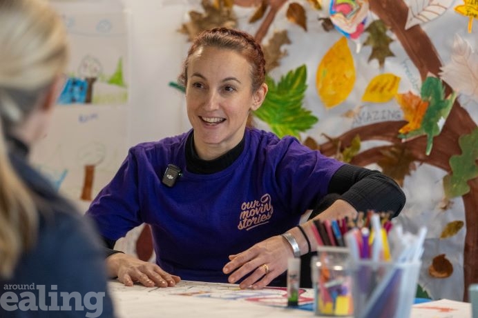 young woman in purple top sitting at an arts and crafts table looking animated