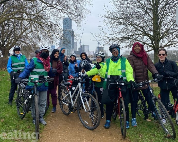 A group of women called the Cycle Sisters posing for a photo, in a park, on their bikes.