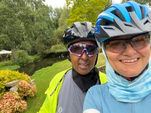 A selfie-style photo of Marian and Sahar from the cycle sisters, wearing their cycle gear with a park in the background.