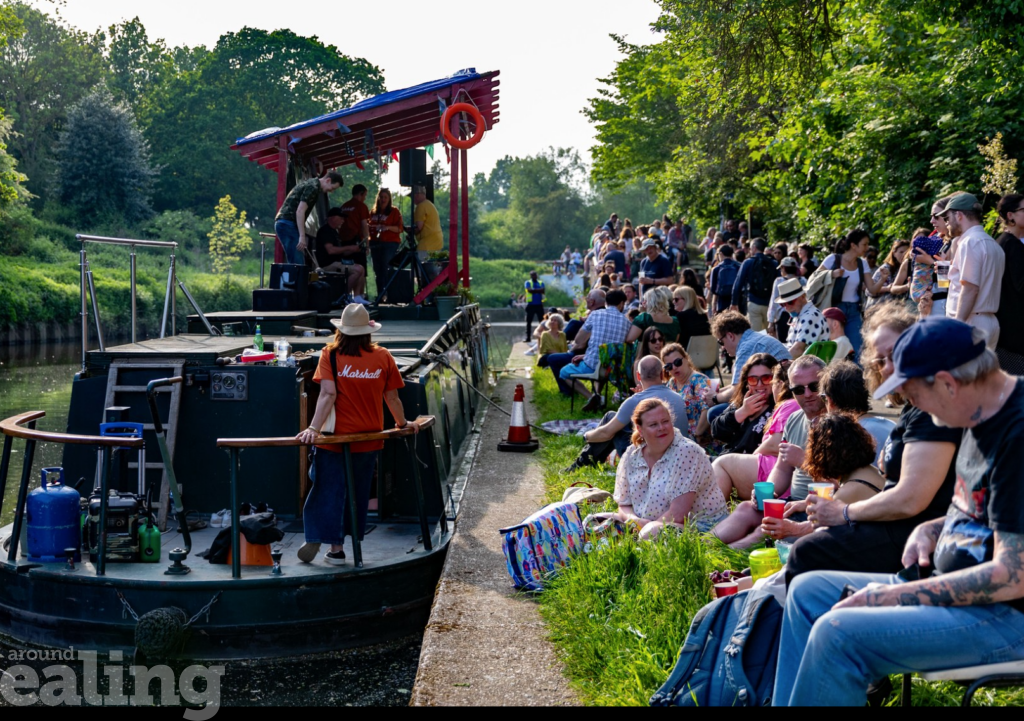 Boat on the Grand Union Canal in Hanwell with music being played and people sitting down enjoying it