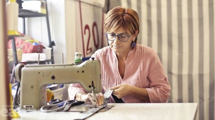 Woman wearing pink shirt using a sewing machine. Photo credit: Andrea Piacquadio